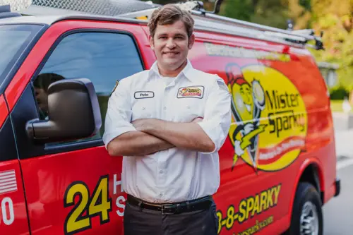 Closeup of Mister Sparky Electrician Tech, Pete, in front of his red service van at a home in Ocala, FL